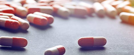 Several red-and-white capsules are scattered across a dark surface in varying orientations.