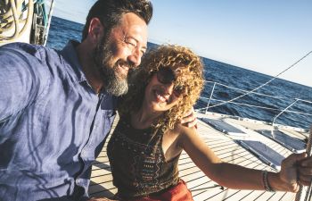 Happy middle-aged couple sailing on a boat.