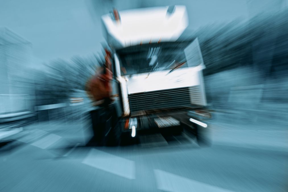 A blurry, stylized image of a white truck moving towards the viewer on a street, with a zoom effect creating motion lines.