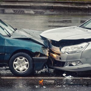 Car accident on wet road during rain, head on collision side view. Two cars damaged after head-on collision, car crash. Car crash on the street, damaged cars after collision. Traffic rules violation