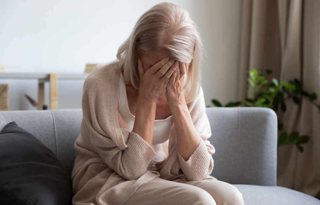 Depressed older woman covering face with hands, crying, feeling desperate. Unhappy mature grandmother experiencing grief, relative’s death, bad news. Stressed elder lady suffering from loneliness.