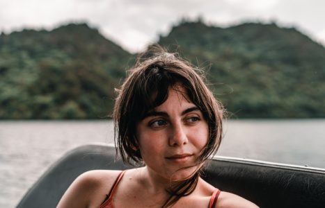 head and face of a disheveled blue eyed caucasian young woman smiling calm and relaxed from a boat sailing on the lake, tarawera lake, new zealand